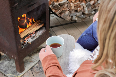 Lake Missoula Tea Company's Big Sky Black Scottish Breakfast tea in a cozy outdoor fireplace setting, showcasing a steaming cup of tea.