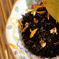 Mango Love Not War tea by Lake Missoula Tea Company in a glass cup, displaying vibrant orange mango tea with fresh fruit slices.