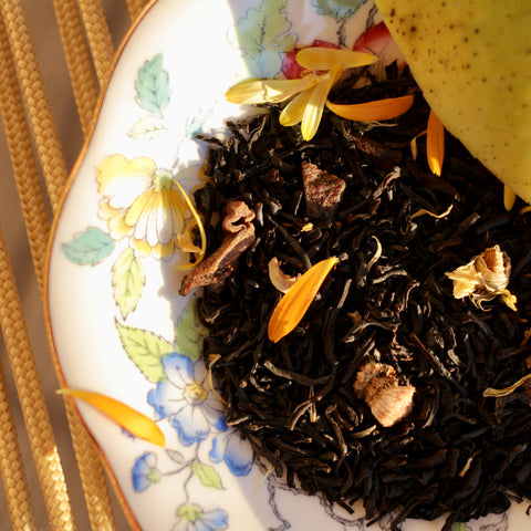 Mango Love Not War tea by Lake Missoula Tea Company in a glass cup, displaying vibrant orange mango tea with fresh fruit slices.