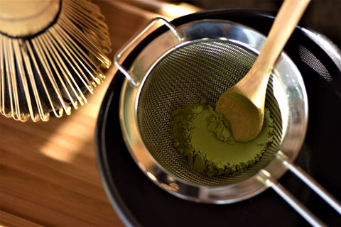 Close-up of Lake Missoula Tea Company's Mammoth Matcha tea in a sieve with a spoon on a tray, ready for preparation.