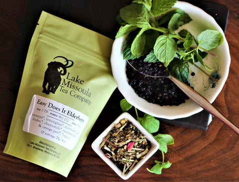 Cup of Easy Does It Elderberry Mint tea by Lake Missoula Tea Company with elderberries and fresh spearmint leaves.