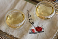 Two cups of Lemon Myrtle tea from Lake Missoula Tea Company on a wooden table, showcasing the herbal tea's fresh lemon aroma.