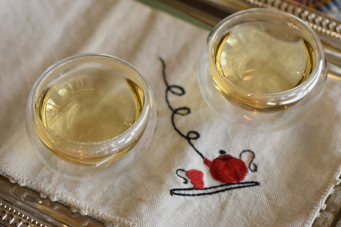 Two cups of Lemon Myrtle tea from Lake Missoula Tea Company on a wooden table, showcasing the herbal tea's fresh lemon aroma.