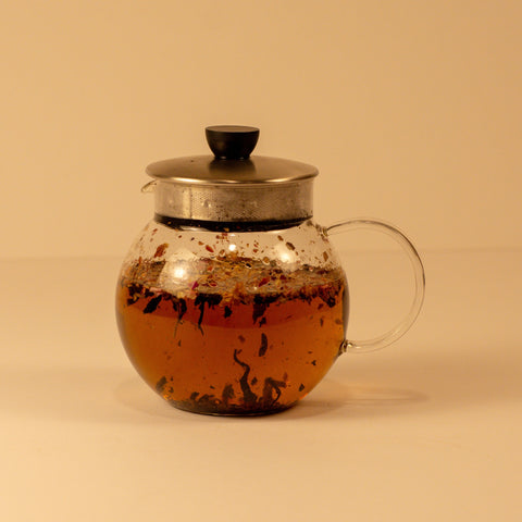 A cup of Rose Chai tea from Lake Missoula Tea Company with rose petals and chai spices in a ceramic mug.