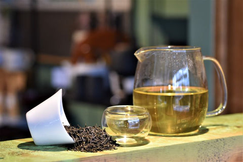 Fresh green Darjeeling District tea leaves in a cup and carafe, brewed by Lake Missoula Tea Company, showcasing vibrant tea leaves.