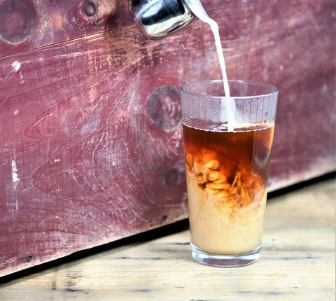 Glass of Lake Missoula Thai Cardamom Tea being poured, showcasing its rich amber color and aromatic infusion in a clear glass.