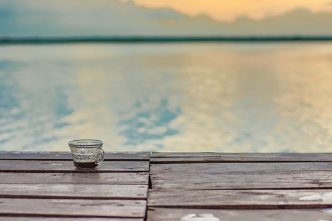 A cup of Lake Missoula Tea Company's Joint Peace Arthritis Blend herbal tea on a wooden dock with a scenic lake background.
