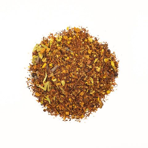 Cup of Lake Missoula Tea Company's Turmeric Ginger Twirl tea with vibrant ginger and turmeric root slices on a rustic surface.