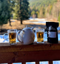 Cup of Lychee Black tea from Lake Missoula Tea Company on a porch with lush backyard scenery.