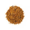 Cup of Sassy Citrus & Spice tea by Lake Missoula Tea Company with citrus slices and spice garnishes on a rustic table.