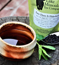 A spoonful of Easy Does It Elderberry Mint tea from Lake Missoula Tea Company, showing dried elderberries and mint leaves.