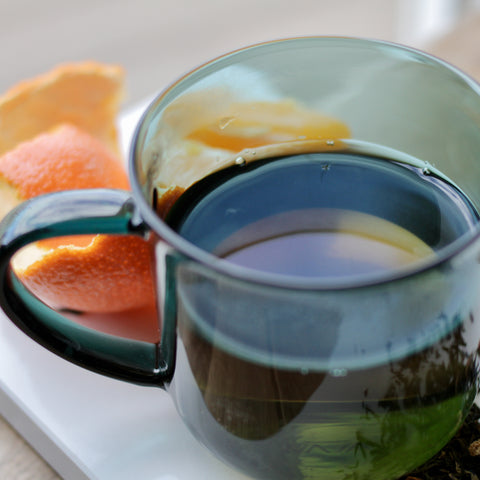 Empress Grey tea by Lake Missoula Tea Company shown in a teacup with loose grey tea leaves and a rainy grey background.