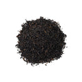 Cup of Lake Missoula Tea Company's Vanilla Crème tea in a white mug, with vanilla beans and tea leaves on a wooden surface.