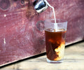 Glass of brewed Thai Cardamom Tea from Lake Missoula Tea Company, showing rich amber color and fresh tea pouring into a glass.