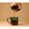 Organic green Rooibos tea from Lake Missoula Tea Company in a clear glass cup with vibrant green leaves.