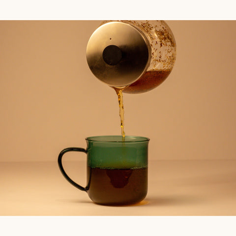 Organic green Rooibos tea from Lake Missoula Tea Company in a clear glass cup with vibrant green leaves.