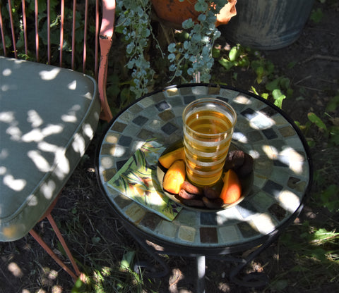 A cup of Peach Peridot Oolong tea from Lake Missoula Tea Company featuring apricot green tea leaves and fresh peach slices.