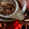 Glass cup of blood orange rooibos tea from Lake Missoula Tea Company with fresh orange slices and a tea infuser.