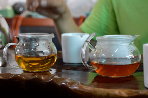 Brewed Dragonwell green tea in a clear glass cup, brewed by Lake Missoula Tea Company, showcasing fresh green tea leaves.
