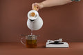 Fellow Corvo white tea being poured from Lake Missoula Tea Company's KaPow! Ginkgo Brain Tea in a clear glass teapot.