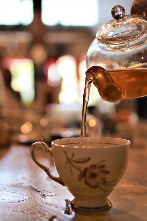 Spicy Yerba Chai tea from Lake Missoula Tea Company displayed in a mug with a tea infuser on a wooden table.
