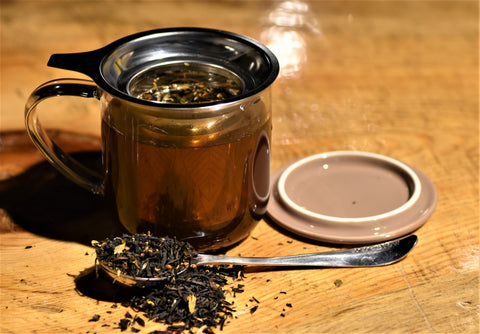 Ginger Orange Puerh tea leaves in a spoon, showcasing vibrant orange and ginger pieces from Lake Missoula Tea Company.