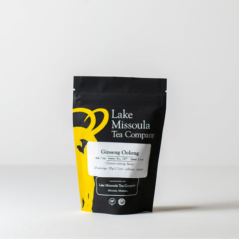 A 50g package of Lake Missoula Tea Company's Ginseng Oolong tea with loose tea leaves and ginseng roots.