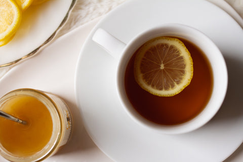 A cup of Lake Missoula Tea Company's cinnamon orange spice tea with orange slices and cinnamon sticks on a wooden table.