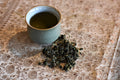 Cup of Jiaogulan Immortality Herb tea in a glass mug, showing fresh green Jiaogulan leaves and brewed herbal tea.