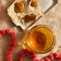 Holiday Tea Bundle from Lake Missoula Tea Company: a glass cup of Big Sky Salted Caramel Tea beside wrapped caramels on a silver tray