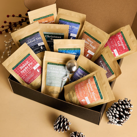 Gift box filled with Winter Collection tea pouches and a tea infuser, with pinecones