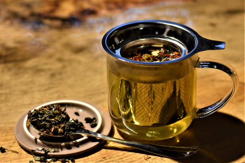 Cup of Mimosa Oolong tea from Lake Missoula Tea Company, showing a brewed golden tea in a clear glass cup with a tea bag tag.
