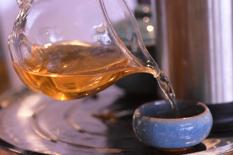 Golden Monkey tea being poured from a gaiwan, showcasing its rich amber color in a traditional tea brewing setting.