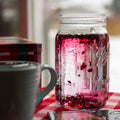 Square image of Lake Missoula Tea Company's hibiscus tea packaging with botanical illustrations on a winter garden background.