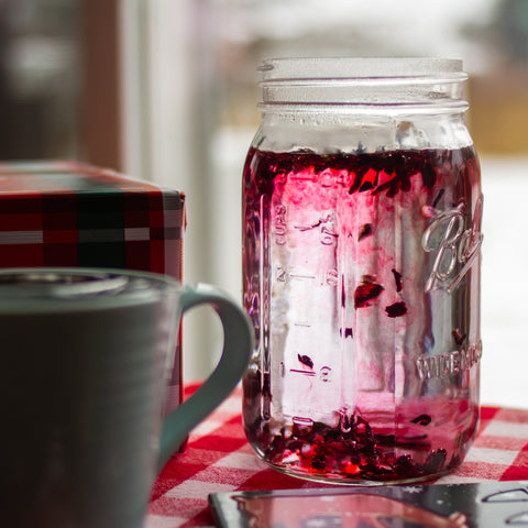 Square image of Lake Missoula Tea Company's hibiscus tea packaging with botanical illustrations on a winter garden background.
