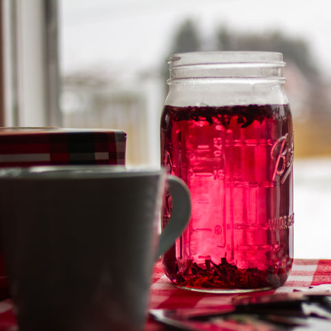 Square image of Lake Missoula Tea Company's hibiscus tea package with winter gardening background, natural and vibrant design.