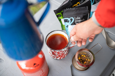 Cup of Good Hope herbal tea from Lake Missoula Tea Company in a white ceramic mug, steam rising, set on a rustic wooden surface.
