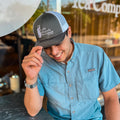 Uriah wearing a Lake Missoula Tea Company trucker hat with mesh back and embroidered front logo.