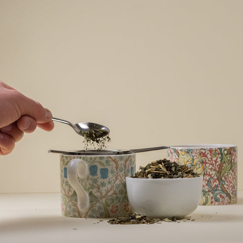 Lake Missoula Tea Company Who Chic herbal tea in a clear glass cup with loose tea leaves and a steaming hot brew.