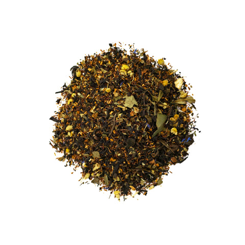 A cup of Sweet Chamomile black tea from Lake Missoula Tea Company with chamomile flowers and tea leaves on a wooden table.
