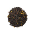 Honey Ponderosa tea by Lake Missoula Tea Company in a clear glass cup with a golden hue and tea leaves nearby.