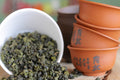 Lake Missoula Gunpowder Pearls tea displayed in a clear glass container with loose green tea leaves and pearls.