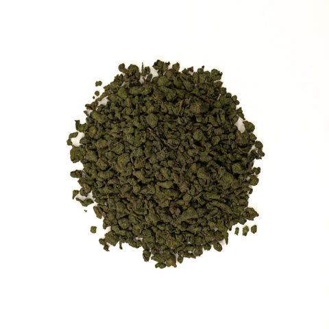 Cup of Lake Missoula Tea Company's Ginseng Oolong tea in a white mug with dried ginseng and oolong tea leaves nearby.