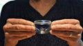 Fingers holding a blue glass cup of Butterfly Pea Flower tea from Lake Missoula Tea Company, vibrant blue color and floral infusion visible.