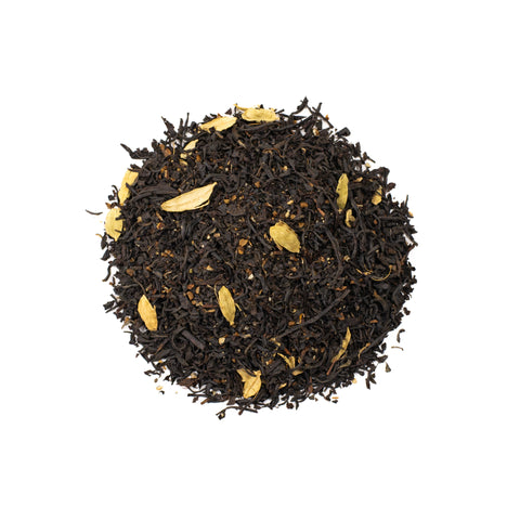 A cup of Lake Missoula Tea Company's Cardamom Thai Tea with a rich amber color and fresh tea leaves in the background.