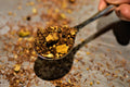 Close-up of Lake Missoula Tea Company's Turmeric Ginger Twirl tea in a scoop, showing vibrant turmeric and ginger pieces.