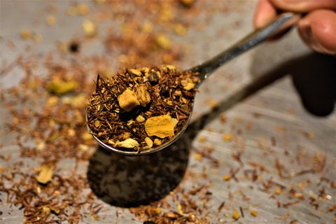 Close-up of Lake Missoula Tea Company's Turmeric Ginger Twirl tea in a scoop, showing vibrant turmeric and ginger pieces.