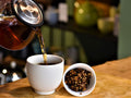 Pouring brewed Turmeric Ginger Twirl tea by Lake Missoula Tea Company in a clear glass cup. Rich, warm tea with turmeric and ginger flavors.