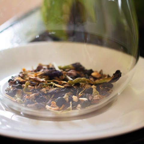 Cup of Stress Less herbal tea by Lake Missoula Tea Company in a white teacup with tea leaves and herbs visible.