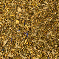 Relaxing Zen Cleanse tea from Lake Missoula Tea Company in a clear glass cup with fresh herbs and tea leaves.